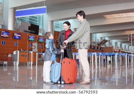 family with red suitcase standing in airport hall