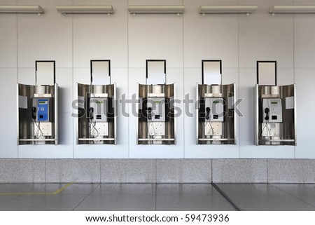 many public phones in big hall with white walls and granite floor