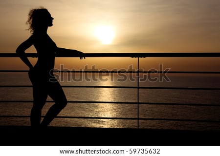 silhouette of curl girl standing on cruise liner deck, hand on rail, side view, sunset on background