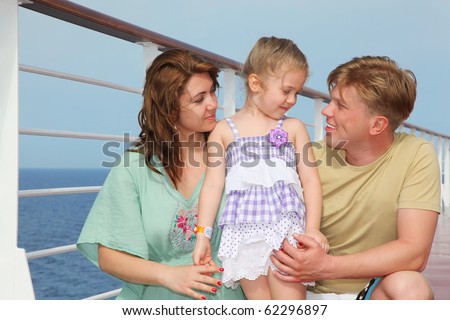 Happy parents with small daughter enjoy sea on yacht