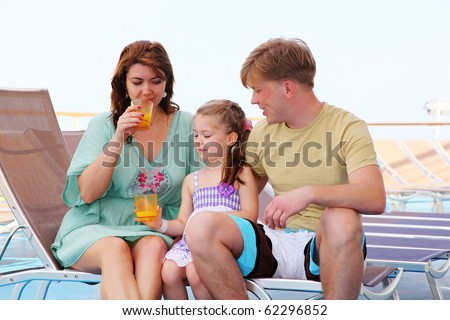 mom dad and daughter rest on deck of yacht and drink tasty juice