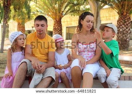 Father, mother and two daughters listen to the story the boy. summer, palm trees, hot summer