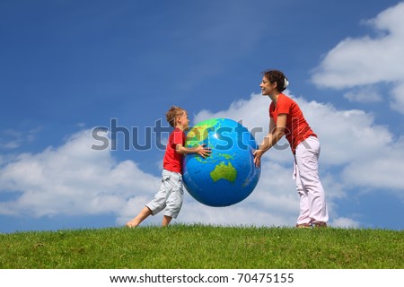Mother with  son play an inflatable globe in  day-time stand  on  grass