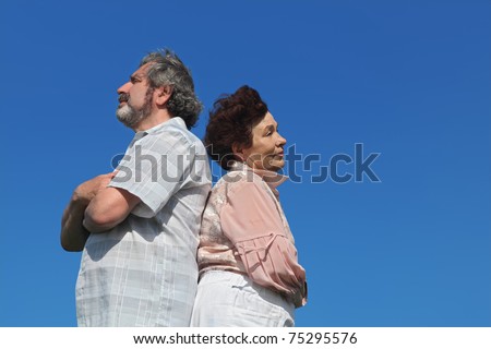 old woman and man standing back to back, crossed hands