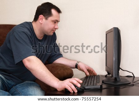 man works at computer at home, concentrated serious face