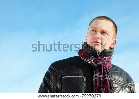 Fellow in  jacket concentrated looks in distance on winter blue sky