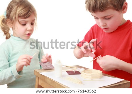 little girl and boy in red T-shirt crafts at small table, girl talking