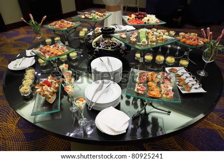 Table with cold snacks and tableware on luxury stand-up party