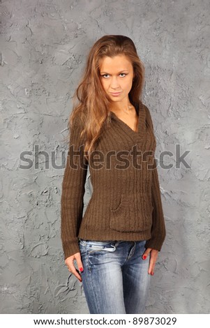 beautiful girl wearing blouse and jeans stand near grey wall