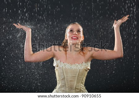 beautiful girl wearing in dress smiles in rain and catches drops by hands