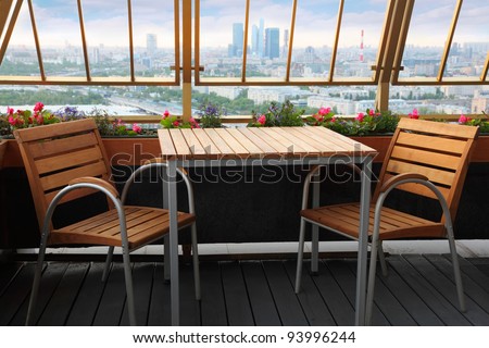 Wooden chairs and table at terrace in empty restaurant; panorama of Moscow