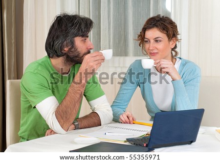 Young man and woman take a break from studying in front of the computer to have some coffee and a chat.