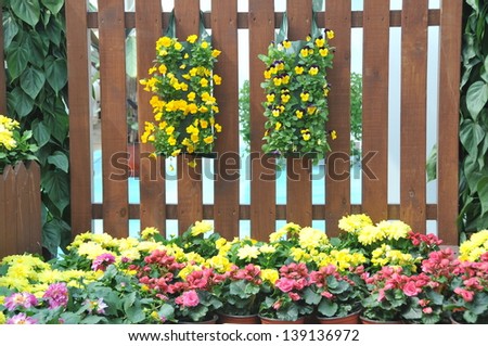 A brown fence in the garden with flowers and plants