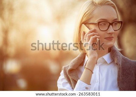 intelligent beautiful woman is using her smart phone, sunset background