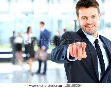 Portrait of smiling mature business man pointing at you in office
