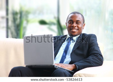 Attractive African American smiling at computer, while sitting at a desk typing on keyboard. Square