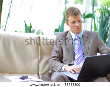 Casual looking businessman working on laptop computer in front of office window