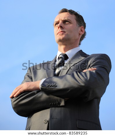 business man in a blue shirt against the blue sky. a symbol of leadership, success and freedom.