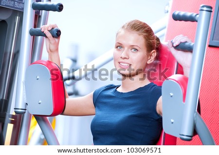 Woman at the gym exercising on a machine. Arm exercise