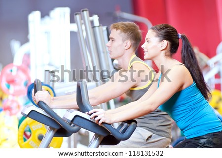 Group of two people in the gym, exercising their legs doing cardio cycling training
