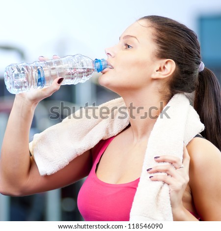 Young oman drinking water after sports. Fitness gym.