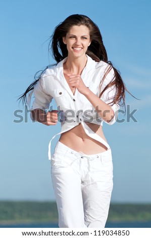 Beautiful young sport woman running in sea coast on sunny summer day