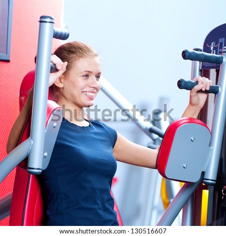 Woman at the gym exercising on a machine. Arm exercise