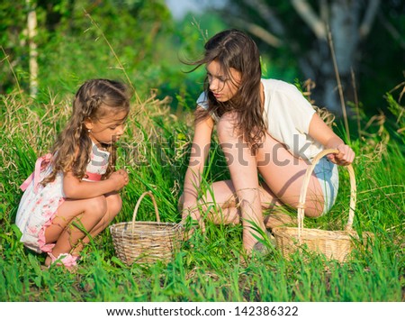 Harvests of berries and mushrooms - lovely girls with the basket of ecological harvests