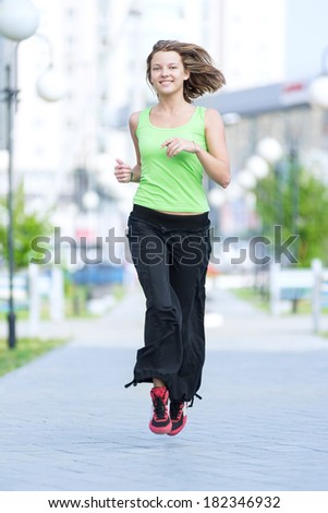 Running woman jogging in city street park at beautiful summer morning. Sport fitness model caucasian ethnicity training outdoor.