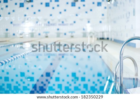 Interior of public indoor swimming pool witch racing Lanes and blue water