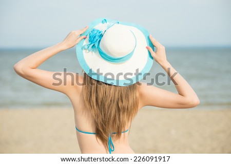 Young lady sunbathing on a beach. Beautiful woman posing at the summer sand beach. Outdoor summer portrait of pretty sport style woman in blue bikini.