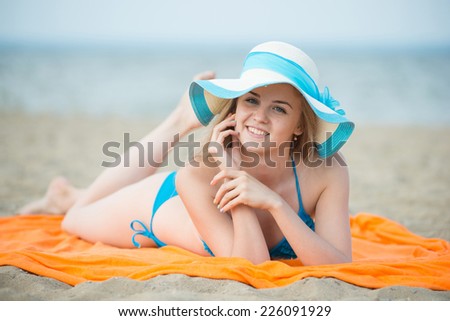 Young lady sunbathing on a beach. Beautiful woman posing at the summer sand beach. Outdoor summer portrait Ocean sea coast. Beautiful fit tan girl. Sexy slim model caucasian ethnicity outdoors.