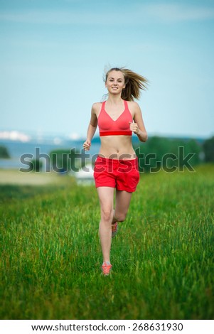 Young lady running. Woman runner running through the summer park rural road. Workout in a park. Beautiful fit girl. Fitness model caucasian ethnicity outdoors. Weight loss exercise. Jogging.