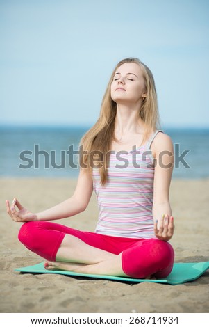 Young lady practicing yoga. Beautiful woman posing at the summer sand beach. Workout near ocean sea coast. Beautiful fit tan girl. Fitness model caucasian ethnicity outdoors. Weight loss exercise