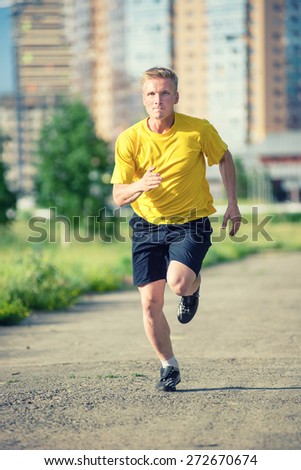 Running man jogging in city street park at beautiful summer day. Sport fitness model caucasian ethnicity training outdoor.