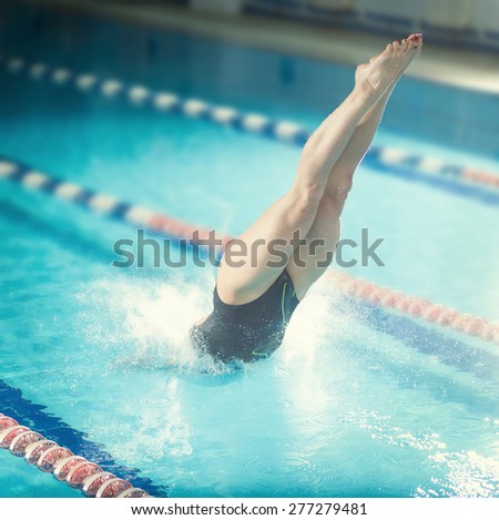 Portrait of a female swimmer, that jumping and diving into indoor sport swimming pool. Sporty woman.