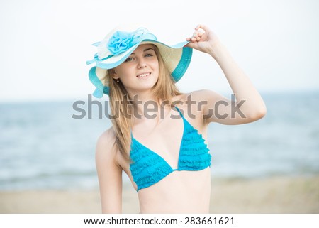 Young lady sunbathing on a beach. Beautiful woman posing at the summer sand beach. Outdoor summer portrait of pretty sport style woman in blue bikini. Ocean sea coast. Beautiful fit tan girl. Sexy