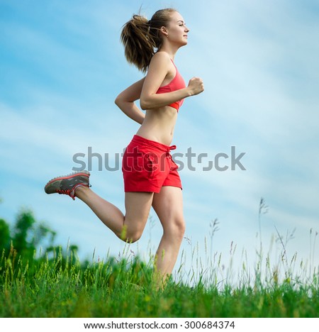 Young lady running. Woman runner running through the summer park rural road. Workout in a park. Beautiful fit girl. Fitness model caucasian ethnicity outdoors. Weight loss exercise. Jogging.
