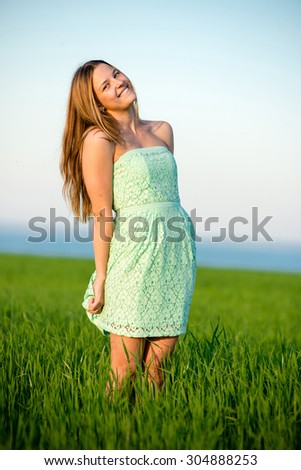 Happy playfull vitality freedom girl stands in green field. Woman lifestyle