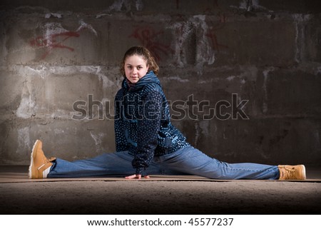 Hip hop girl dancing in modern style over urban grey brick wall