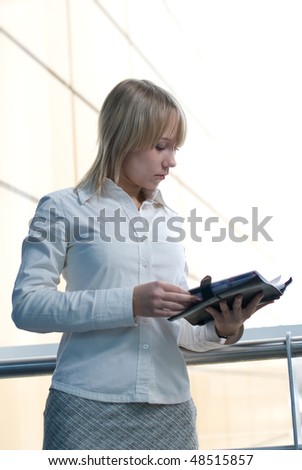 Attractive young businesswoman with day planner in office lobby
