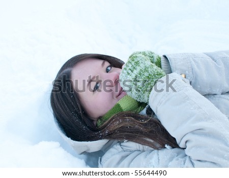 Winter lifestyle. Beautiful girl lying in snow. Snow angel