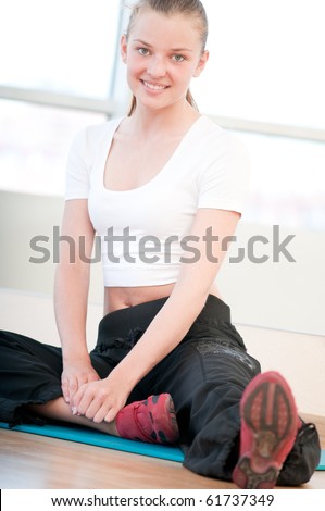 Young woman doing yoga exercises on floor at the sport gym