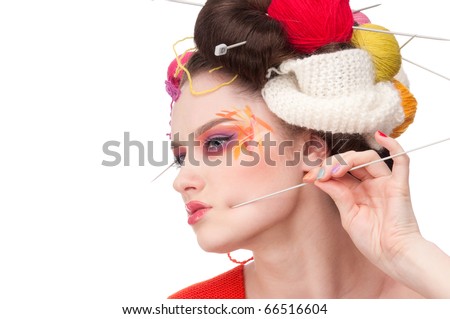 Closeup portrait of beautiful fashion woman with color face art. All in knitting style. Wool balls. Pain.