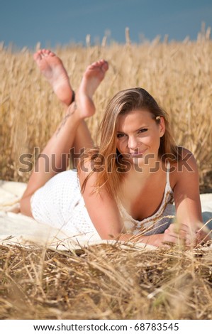 Beautiful woman in white dress with perfect hair and skin posing in wheat field on sunny summer day. Picnic.