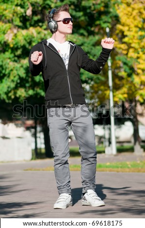 young casual cheerful man dancing outdoor in city park