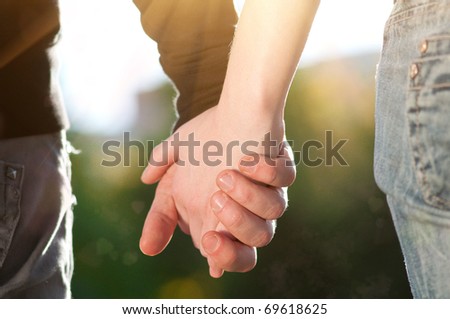 Concept shoot of friendship and love of man and woman: two hands over sun ray and nature