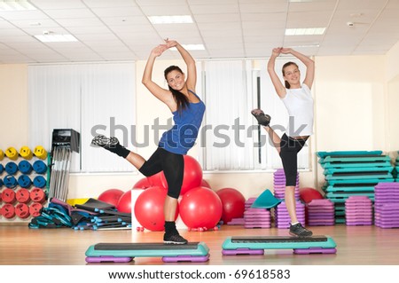 Two beautiful sport woman doing stretching fitness exercise at sport gym. Step.