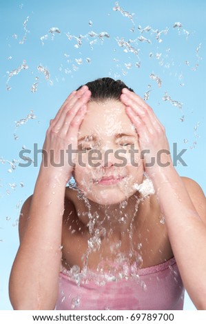 Closeup portrait of young beautiful girl in bath that washing face in cold fresh water. Splash and fun!