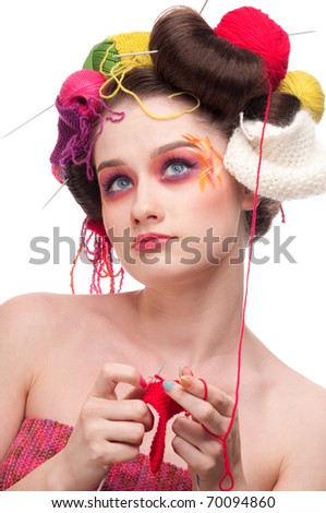 Closeup portrait of beautiful fashion woman with color face art. All in knitting style. Wool balls. Dreams
